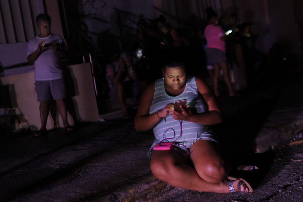 A woman checks her cellphone next to a road at night in one of the few places with cell signal access in San Juan, Puerto Rico, on Sept. 25, 2017. (Ricardo Arduengo/AFP/Getty Images)
