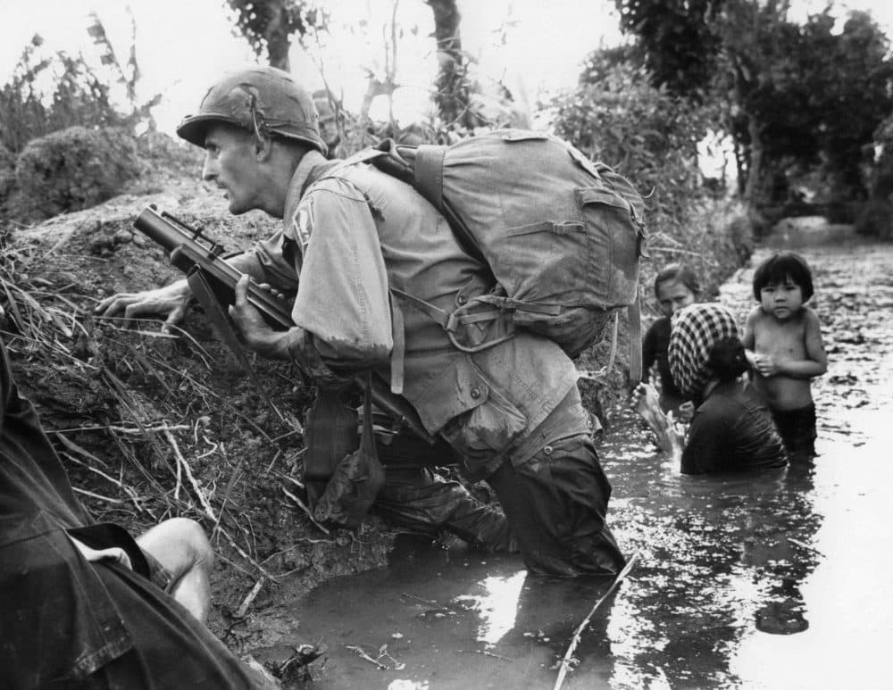  In this Jan. 1, 1966 file photo, a Paratrooper of the 173rd U.S. Airborne brigade crouches with women and children in a muddy canal as intense Viet Cong sniper fire temporarily pins down his unit during the Vietnamese War near Bao trai in Vietnam. Filmmaker Ken Burns said he hopes his 10-part documentary about the War, which begins Sept. 17, 2017 on PBS, could serve as sort of a vaccine against some problems that took root during the conflict, such as a lack of civil discourse in America. (Horst Faas/AP)