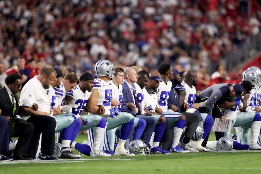 Members of the Dallas Cowboys link arms and kneel during the national anthem last Monday night. (Christian Petersen/Getty Images)