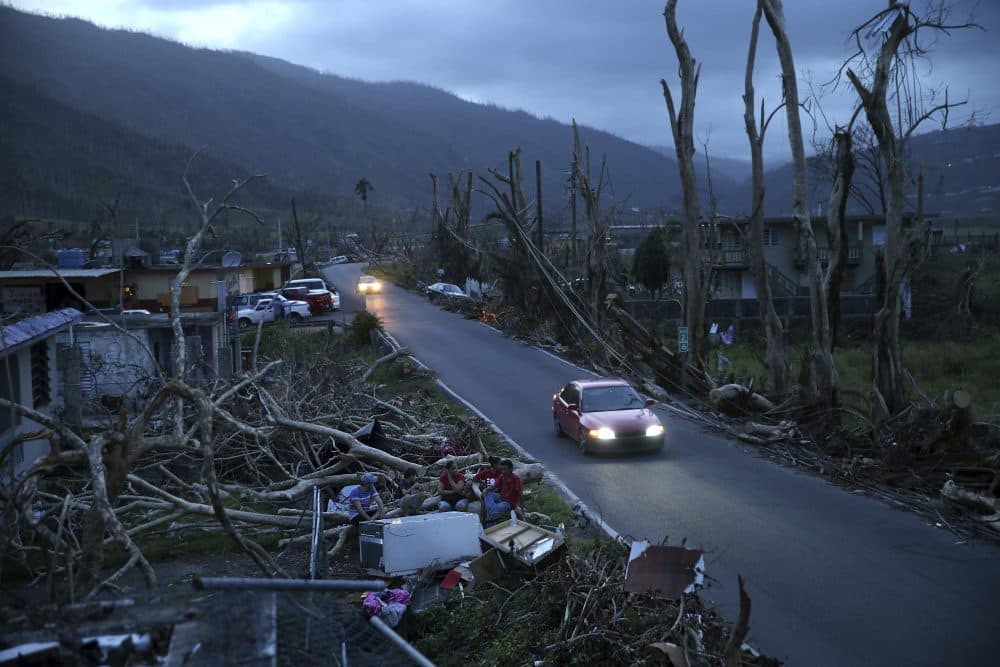 Neighbors sit on a couch outside their destroyed homes as sun sets in the aftermath of Hurricane Maria, in Yabucoa, Puerto Rico on Tuesday, Sept. 26. (Gerald Herbert/AP)