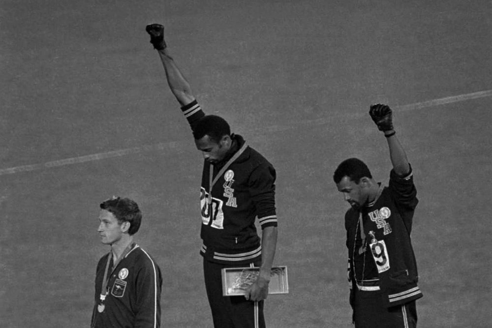Extending gloved hands skyward in racial protest, U.S. athletes Tommie Smith, center, and John Carlos stare downward during the playing of "The Star-Spangled Banner" after Smith received the gold and Carlos the bronze for the 200-meter run at the Summer Olympic Games in Mexico City on Oct. 16, 1968. (AP)