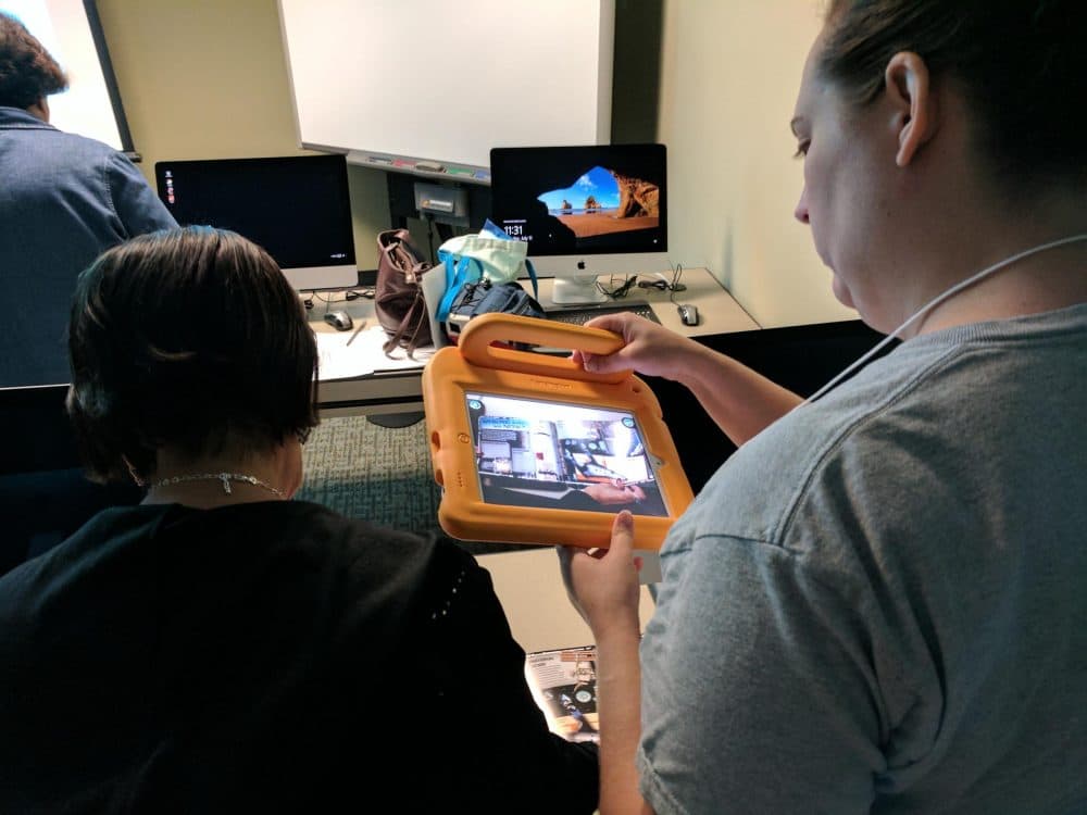 Alice Asevedo (left) and Laura Johansen (right) use iPads to discover what hidden content exists on these AR books. (Paul Flahive/Texas Public Radio)