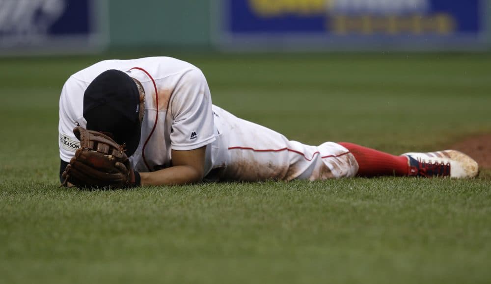 Boston Red Sox shortstop Xander Bogaerts remains on the turf after he was unable to catch up with a ball hit by Josh Reddick, which drove in a run, during the eighth inning in Game 4 of baseball's American League Division Series, Monday, Oct. 9, 2017, in Boston. (AP Photo/Charles Krupa)