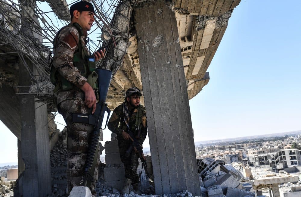 Members of the Syrian Democratic Forces (SDF), backed by U.S. special forces, walk on a building near Raqqa's central hospital as they clear the last positions on the frontline on Oct. 16, 2017, in the Islamic State group jihadists' crumbling stronghold. (Bulent Kilic/AFP/Getty Images)