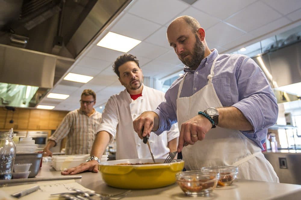 Executive food editor of Cook's Country Bryan Roof, right, cuts into a piece of rib-eye steak they are testing for a recipe for steak pizzaiola as Dan Cellucci looks on. (Jesse Costa/WBUR)
