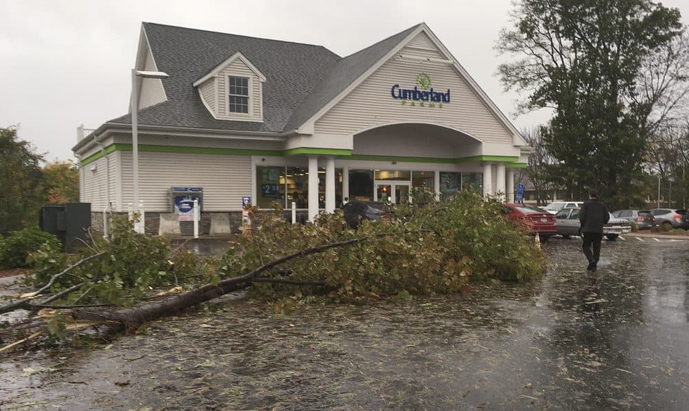 A toppled tree fills part of the parking lot at a Cumberland Farms after an overnight storm on Monday in Glastonbury, Conn. (Dave Collins/AP)
