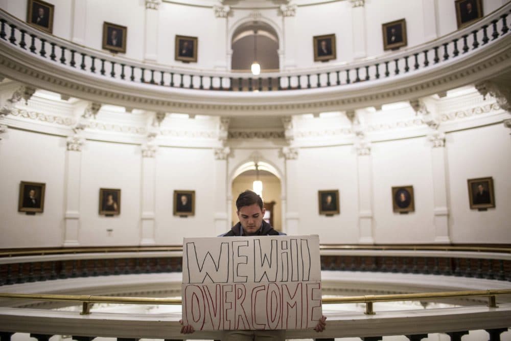 Jacob Rubio holds a sign that reads "We will overcome," in the rotunda of the state Capitol shortly after the Electoral College cast their vote in Austin, Texas, Monday, Dec. 19, 2016. (Tamir Kalifa/AP)