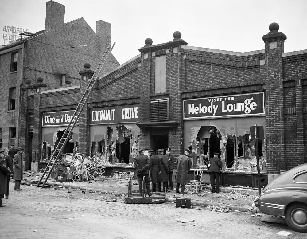 Boston police and firemen watch rear entrance to the Melody Lounge section of the Cocoanut Grove Night Club, Nov. 29, 1942. Debris from broken chairs, table and personal effects of some guests of the club when the fire broke out last night litter sidewalk and gutter. Over 400 people perished. (AP Photo)