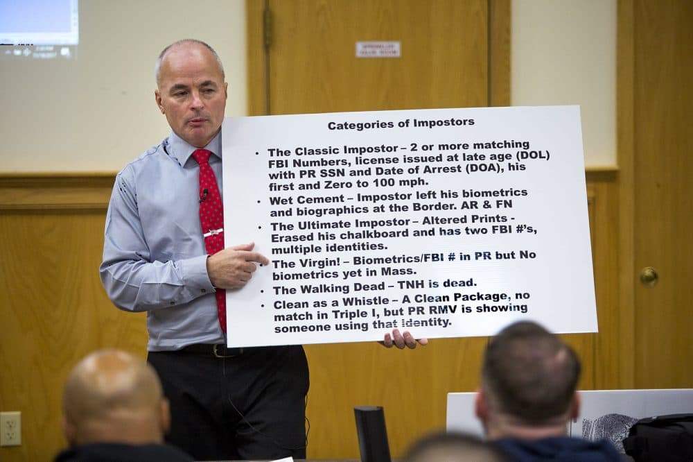 Officer James Scott of the Saugus Police Department holds up a placard with the categories of so-called "impostors" during an impostor training class at Bristol County Jail and House of Correction in North Dartmouth. (Jesse Costa/WBUR)