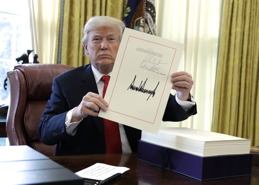 President Trump displays the $1.5 trillion tax overhaul package he had just signed, Friday, Dec. 22, 2017, in the Oval Office of the White House in Washington. Trump touted the size of the tax cut, declaring to reporters in the Oval Office before he signed it Friday that "the numbers will speak." (Evan Vucci/AP)