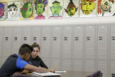 ADVANCE FOR MONDAY, MAY 2, 2016 AND THEREAFTER - In this April 19, 2016 photo, Laurie Millan, a para-professional and tutor, works with a student during an after school tutoring session at San Francisco International High School, in San Francisco. While some districts in numerous states have discouraged migrant minors from Central America from enrolling in their schools, the school accommodated its youths by rewriting young-adult novels at a basic level to spark the newcomers' interest in reading. (AP Photo/Jeff Chiu)