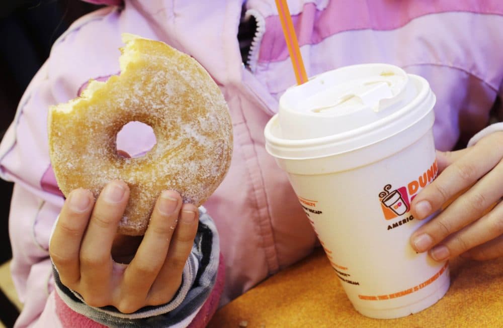 In this 2013 file photo, a girl holds a beverage, served in a foam cup, and a doughnut at a Dunkin' Donuts. (Mark Lennihan/AP)