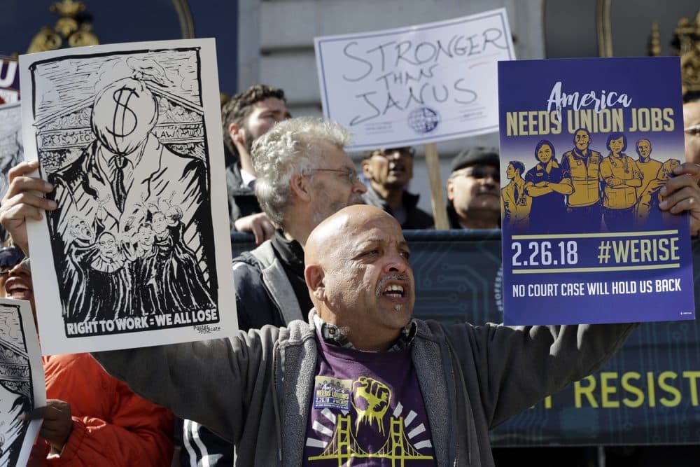 A demonstrator holds pro-union signs during a demonstration involving various labor union groups Monday, Feb. 26, 2018, in San Francisco. The Supreme Court is divided in a major organized labor case over &quot;fair share&quot; fees that nonmembers pay to help cover the costs of contract negotiations. (AP Photo/Marcio Jose Sanchez)
