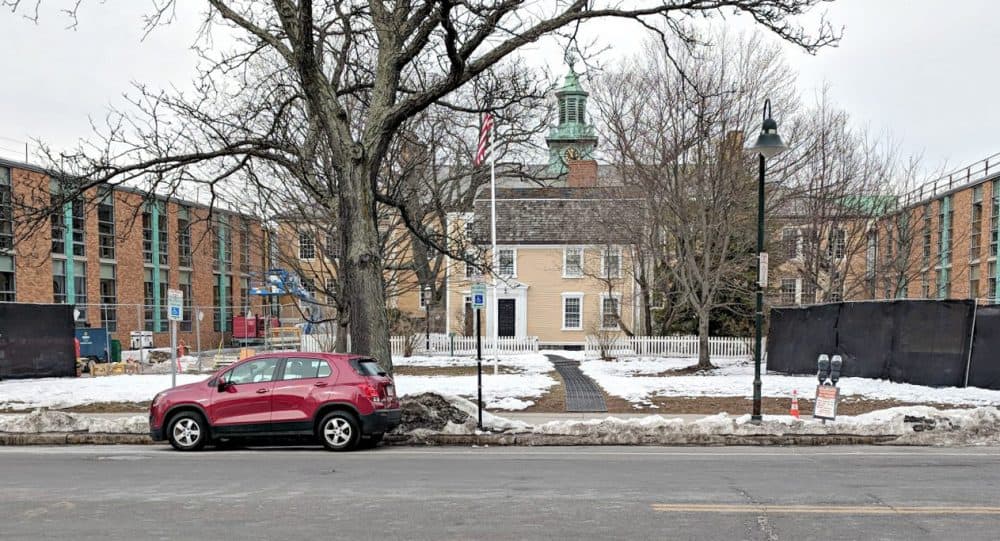 The renaming of a school in Brookline brings up a bigger question, writes Jessica Ullian. Why are certain figures remembered while others are pushed aside?
In this photo: The small yellow structure is the original home of Edward Devotion, circa 1740. The darker yellow structure is the original elementary school. The red-brick structure is the new construction. (Courtesy)