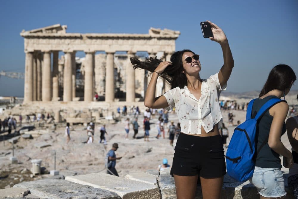 A tourist takes a selfie in front of the the ruins of the fifth century B.C. Parthenon temple at the Acropolis hill, on Friday, Sept. 1, 2017. (AP Photo/Petros Giannakouris)