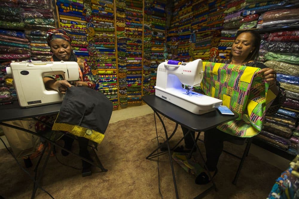 Ebby Ihionu, right, and her sister Ifeyinwa Okolie work on custom clothes made with African fabrics at Elegance African Fashions in Dorchester. (Jesse Costa/WBUR)