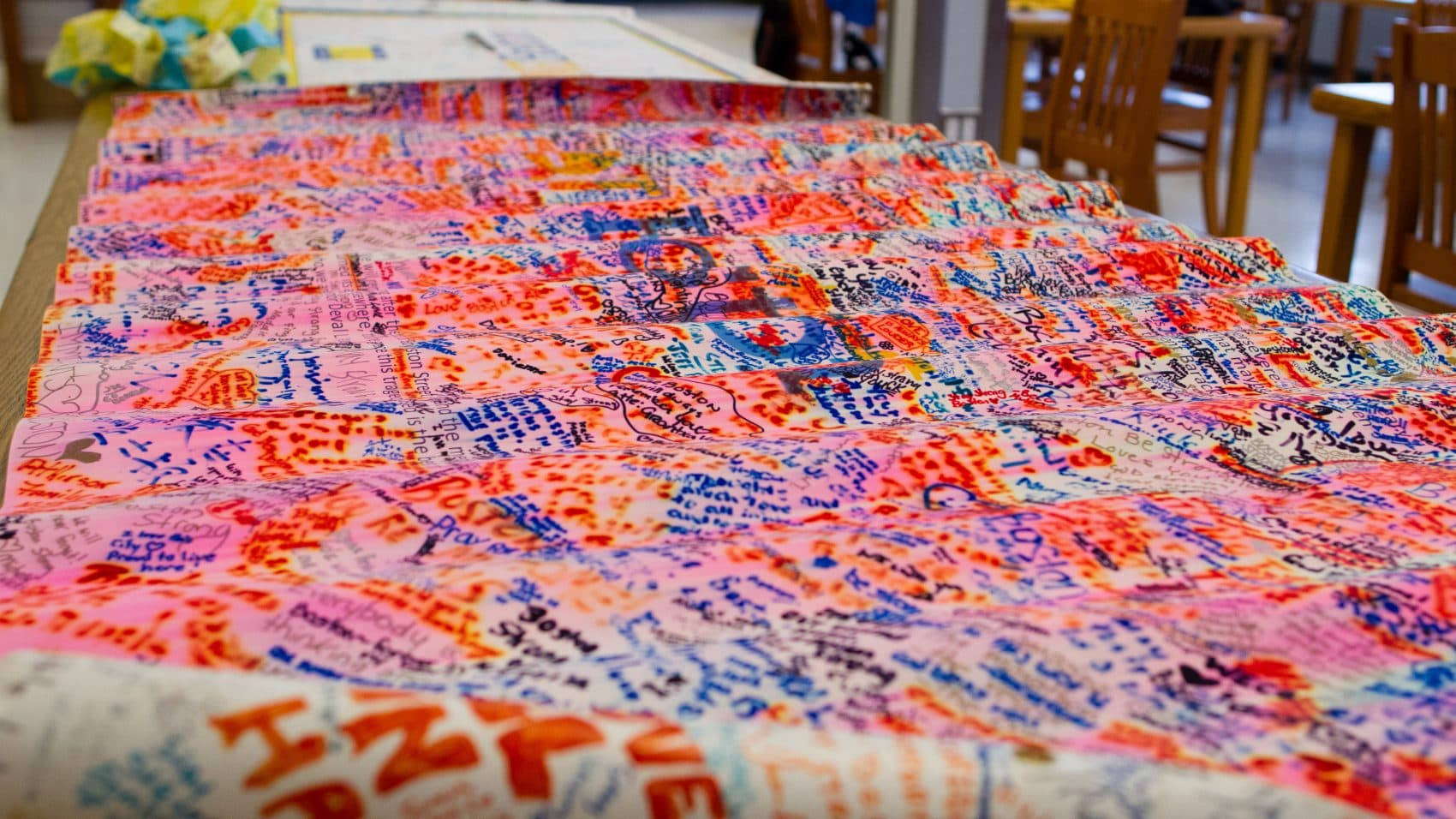 Items from a pop-up memorial following the 2013 Boston Marathon bombing are arranged on tables in the Boston City Archives reading room five years later. (Elizabeth Gillis/WBUR)