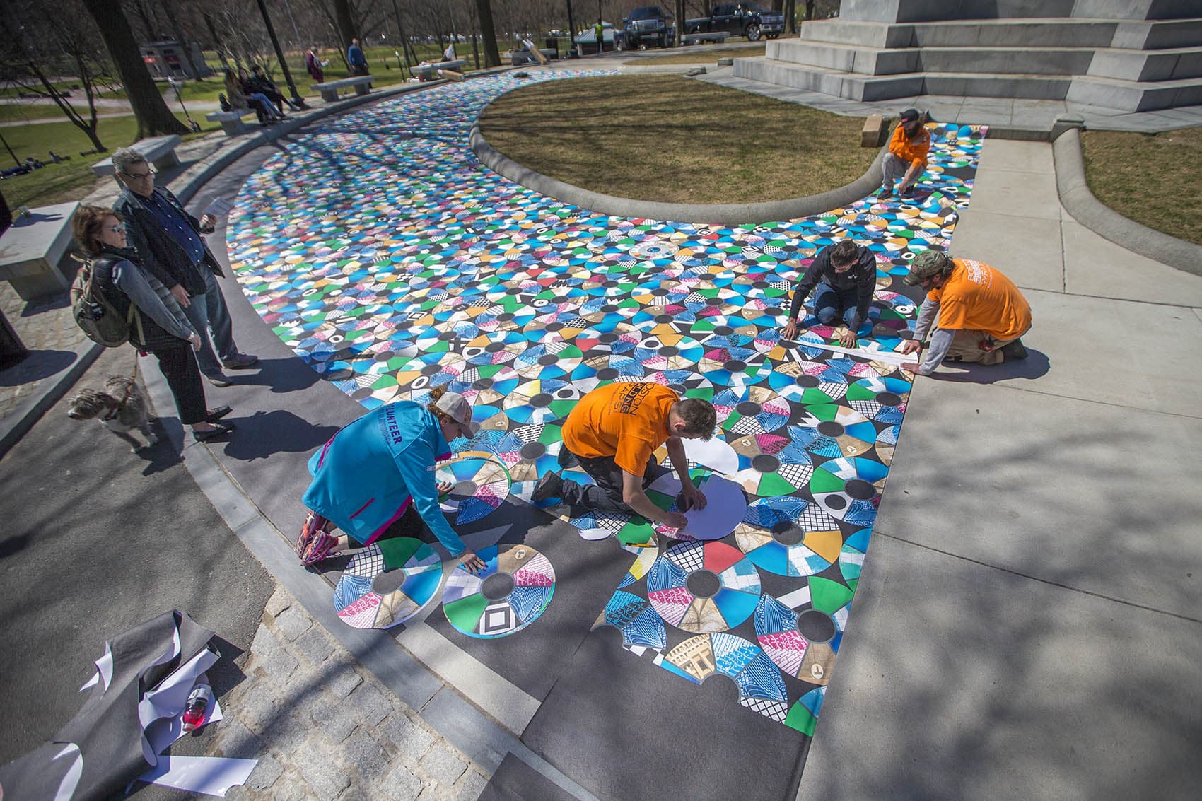 Julia Vogl, in blue, works with a team from Boston Building Wraps to install the "Pathways to Freedom" project around the Soldiers and Sailors Monument on Boston Common. (Jesse Costa/WBUR)