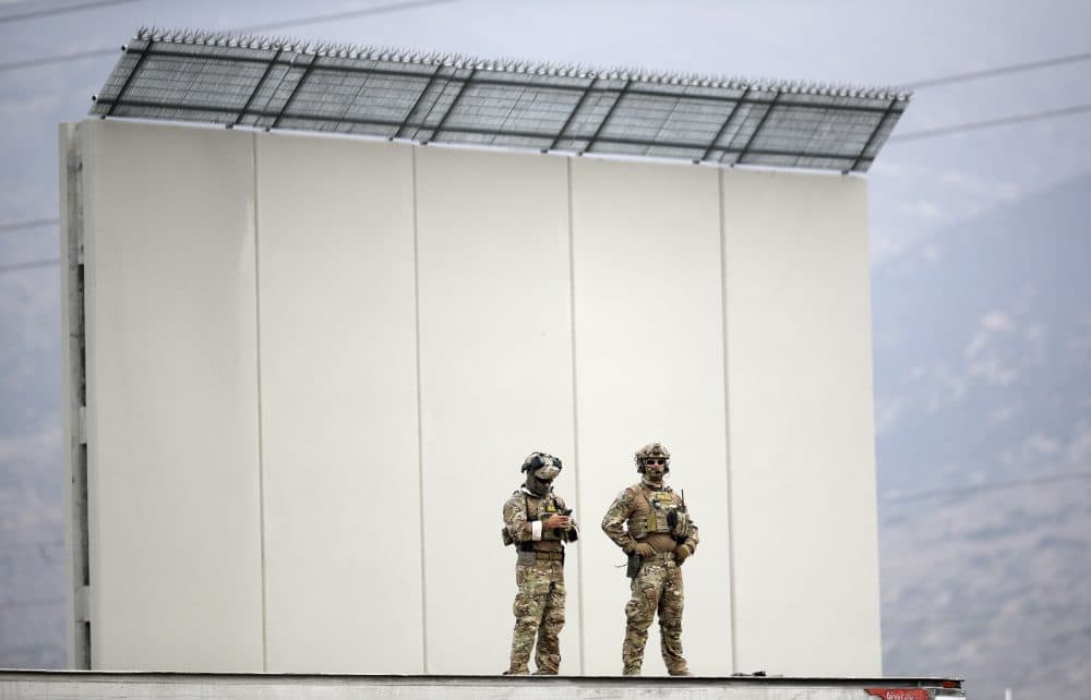 In this March 13, 2018, photo, officials stand guard near one of the border wall prototypes during a visit to San Diego by President Donald Trump, seen from Tijuana, Mexico. (Gregory Bull/AP)