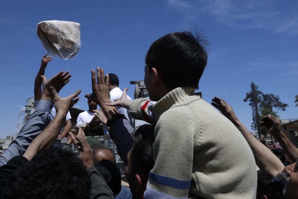 Syrian authorities distribute bread, vegetables and pasta to Douma residents in the town of Douma, the site of a suspected chemical weapons attack, near Damascus, Syria, Monday, April 16, 2018. Two days after Syrian troops declared Douma liberated from opposition fighters, a tour in the city showed the widespread destruction it has suffered since falling under rebel control six years ago. (Hassan Ammar/AP)