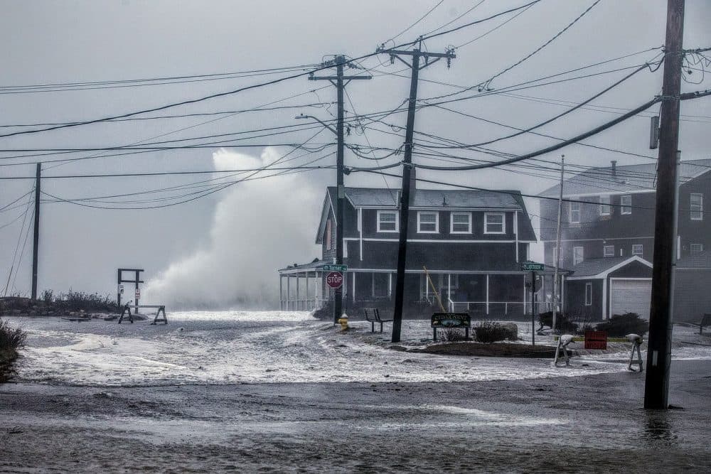 A wave crashes over a house in Scituate during a 2018 northeasterly. (Jesse Costa/WBUR)