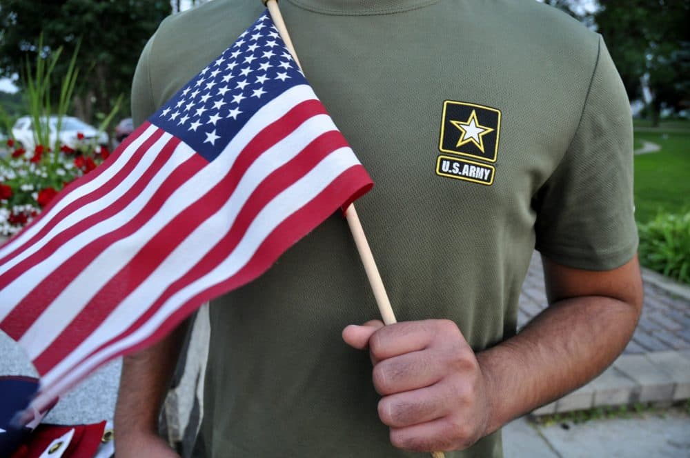In this Tuesday, July 3, 2018 photo, a Pakistani recruit, 22, who was recently discharged from the U.S. Army, holds an American flag as he poses for a picture. The man asked his name and location to be undisclosed for safety reasons. The AP interviewed three recruits from Brazil, Pakistan and Iran, all of whom said they were devastated by their unexpected discharges. (Mike Knaak/AP)