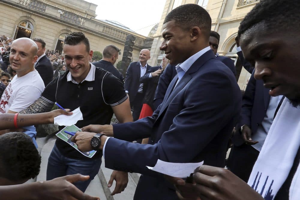 France forward Kylian Mbappe, center, and forward Ousmane Dembele sign autographs during an official reception at the Elysee Presidential Palace in Paris, Monday, July 16, 2018. (Ludovic Marin/AP)