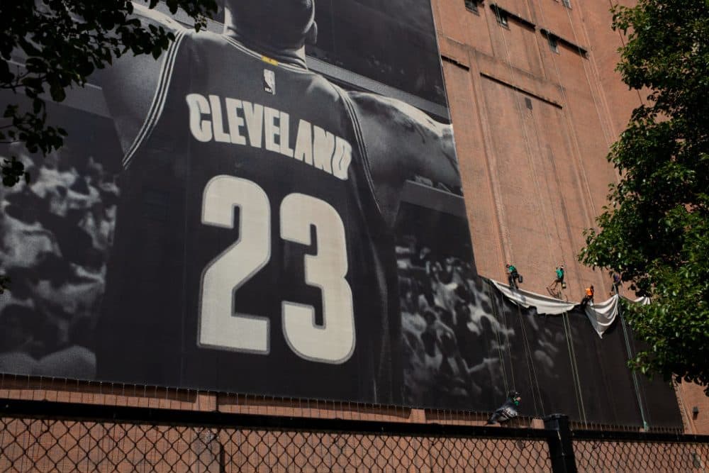 Workers take down the LeBron James banner from Cleveland's Sherwin Williams building. James is on his way to Los Angeles. (Angelo Merendino/Getty Images)