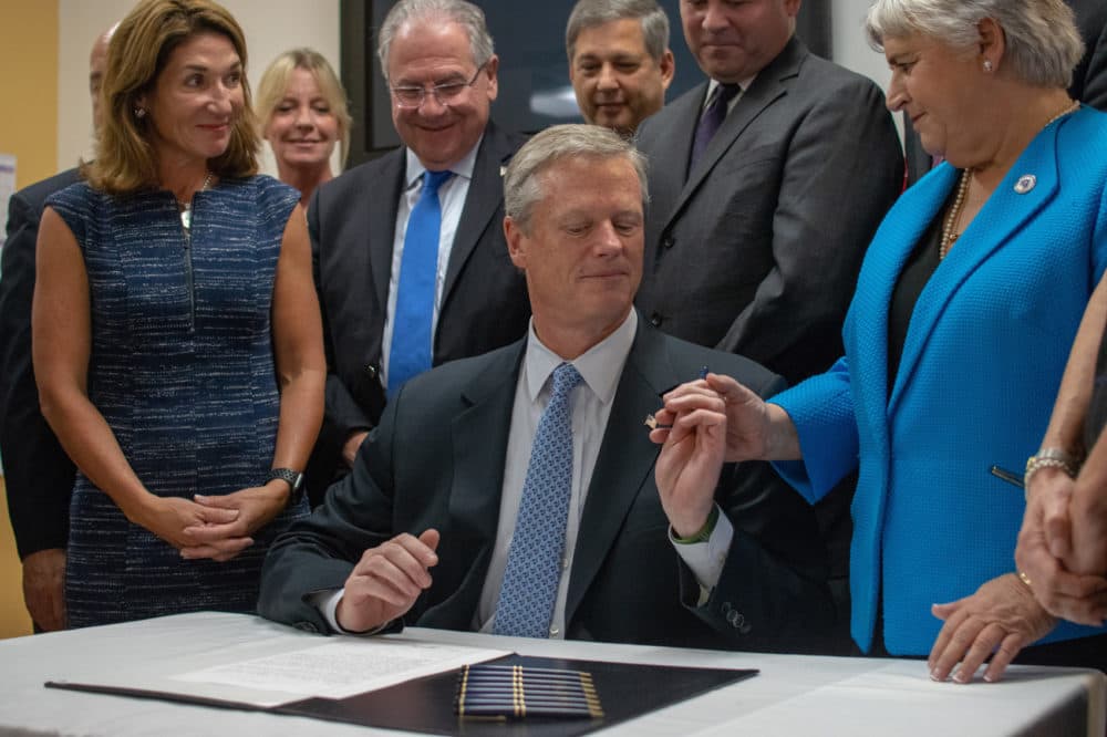 Gov. Charlie Baker handed a ceremonial pen to state Rep. Denise Garlick, co-chairwoman of the Mental Health, Substance Use and Recovery Committee. (Chris Triunfo/SHNS)