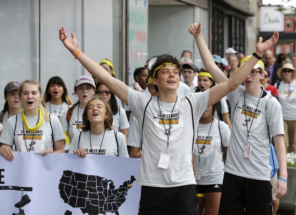 Jack Torres, 16, a Somerville, Mass., high school student, center, raises his arms while walking in a planned 50-mile march, Thursday, Aug. 23, 2018, in Worcester, Mass. The march, held to call for gun law reforms, began Thursday, in Worcester, and is scheduled to end Sunday, Aug. 26, in Springfield, Mass., at the headquarters of gun manufacturer Smith &amp; Wesson. (AP Photo/Steven Senne)