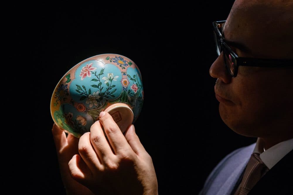 Nicolas Chow, deputy chairman for Sotheby's Asia, holds an extremely rare Qing Dynasty bowl during a media preview at auction house Sotheby's in Hong Kong on March 1, 2018. (Anthony Wallace/AFP/Getty Images)