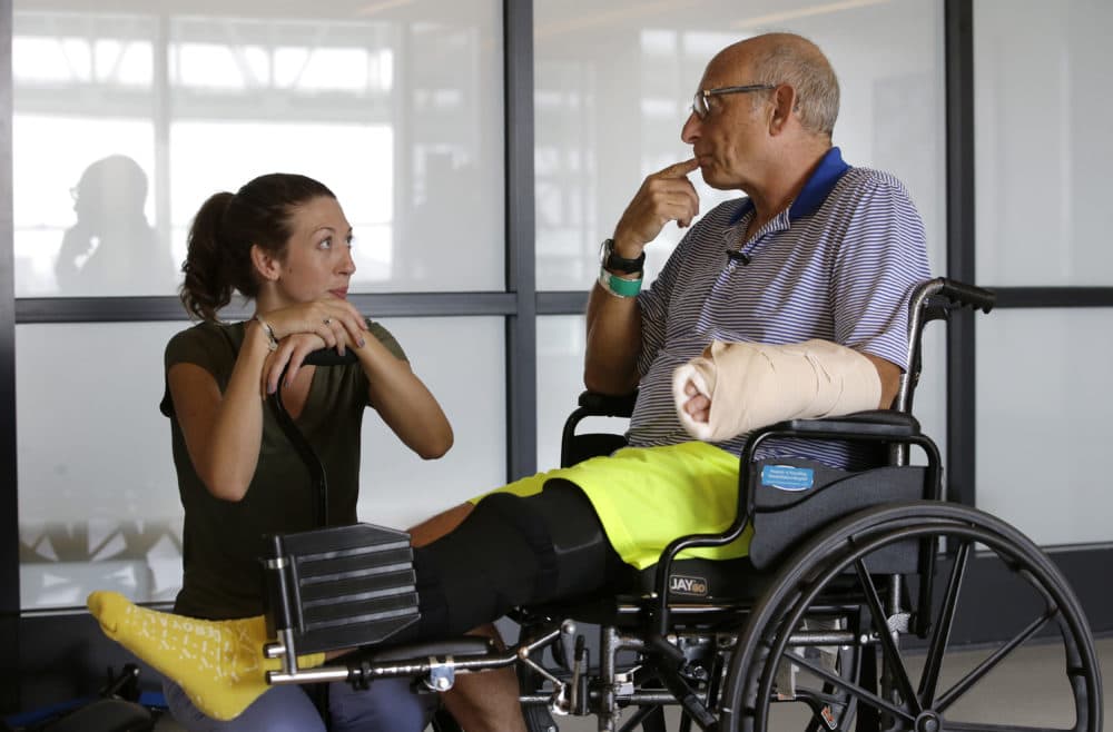 William Lytton, of Scarsdale, N.Y., right, speaks with physical therapist Caitlin Geary during physical therapy at Spaulding Rehabilitation Hospital, in Boston, Tuesday, Aug. 28, 2018, while recovering from a shark attack. Lytton suffered deep puncture wounds to his leg and torso after being attacked by a shark on Aug. 15 while swimming off a beach, in Truro, Mass. Lytton injured a tendon in his arm while fighting off the shark. (Steven Senne/AP)