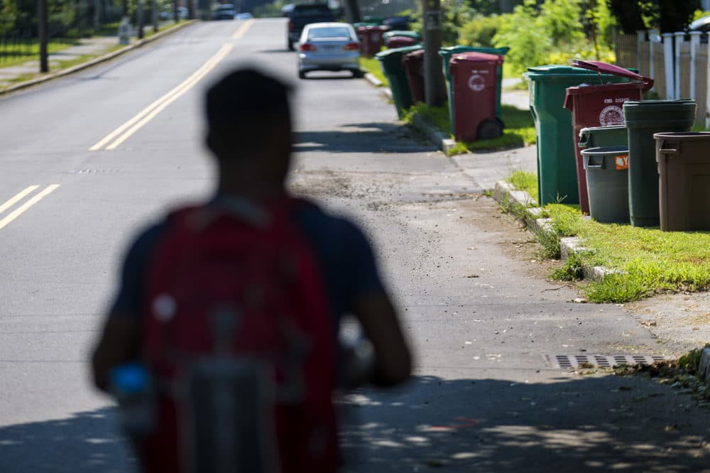Lowell recycling enforcement coordinator Bora Chhun walks down Beacon Street in Lowell. (Jesse Costa/WBUR)
