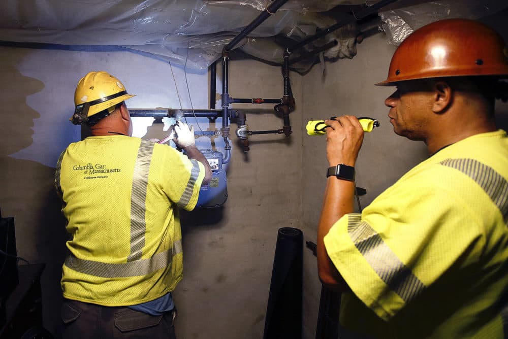 Columbia Gas employee Brian Jones shines a flashlight so his partner, using a wrench, can shut off the gas in a home last September in Andover, Mass. (Winslow Townson/AP)