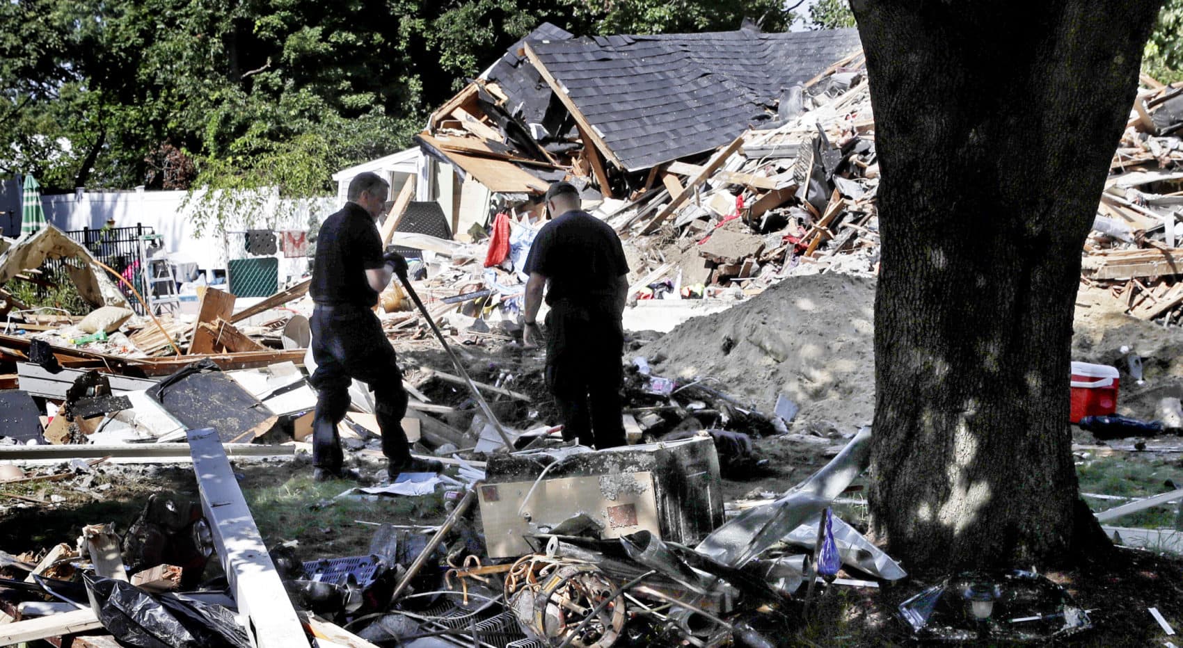 Fire investigators pause while searching the debris at a home which exploded following a gas line failure in Lawrence. (Charles Krupa/AP)