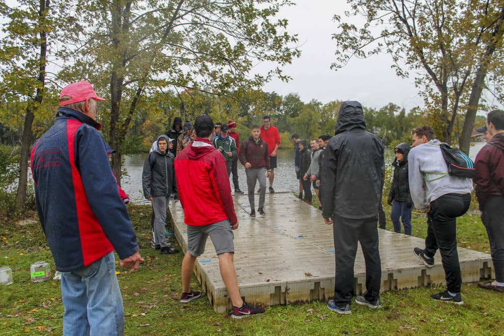 John Born, front and far left, helps direct members of the Boston College men’s crew team as they build docks for the Head of the Charles. (Hannah Chanatry/WBUR)