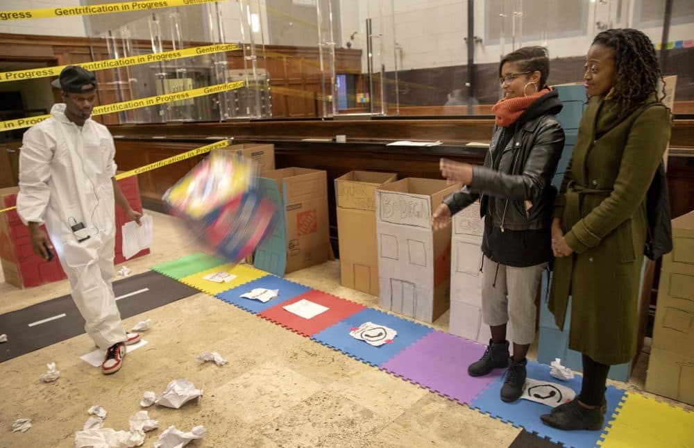 Veronica Wells (with reporter Jacquinn Sinclair alongside her) throws the dice to see how far she can get around the board. "I felt the game was rigged," she says after playing the game. "I've felt that in real life." (Robin Lubbock/WBUR)