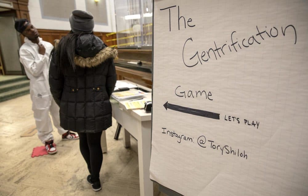 Artist Tory Bullock invites a contestant to play "The Gentrification Game." (Robin Lubbock/WBUR)