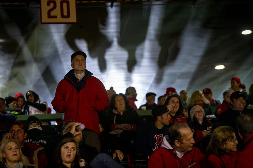 A man stands up to watch the Red Sox take the field. (Jesse Costa/WBUR)