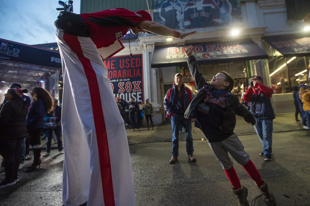 Six-year-old Nicholas Field of Newton leaps in the air to high five Big League Brian on Jersey Street. (Jesse Costa/WBUR)