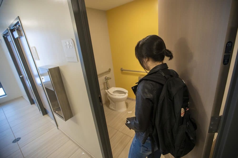 UMass Boston student Chanel An enters one of the toilet and shower rooms in the open concept, all-inclusive bathroom at a new dorm building. (Jesse Costa/WBUR)