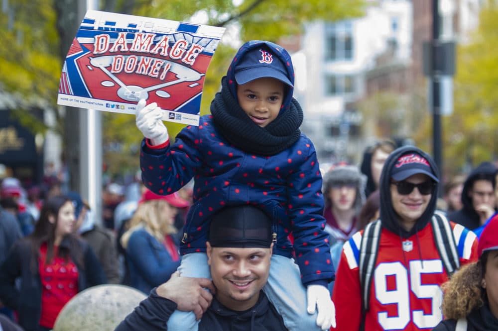 Six-year-old Jazmyn Pollanco sits on her dad’s shoulder during the Red Sox World Series celebration on Boylston Street. (Jesse Costa/WBUR)