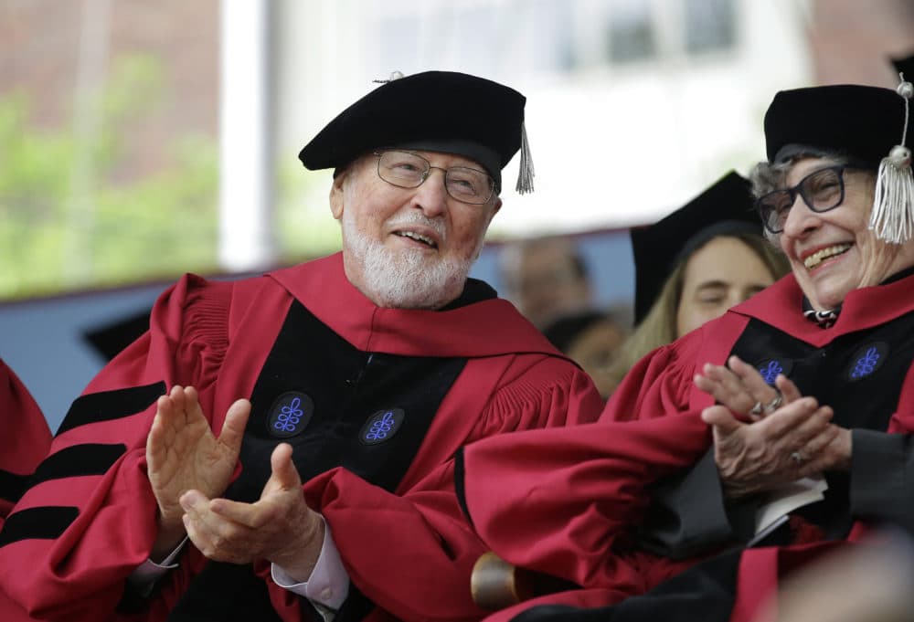 Composer John Williams, left, applauds along with literary critic, author, and feminist Sandra Gilbert, right, during Harvard University commencement exercises in 2017. Williams received an honorary Doctor of Music degree, while Gilbert received an honorary Doctor of Laws degree Thursday. (Steven Senne/AP)