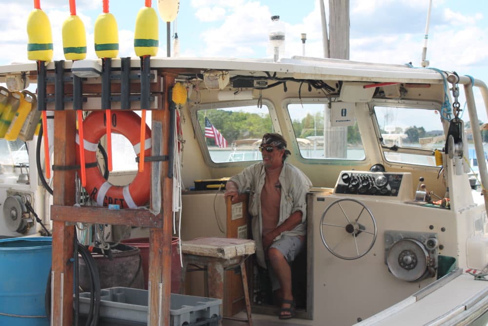 Peter Fredrickson sits on his boat No Regrets, docked in the Hingham marina. (Hannah Chanatry/WBUR)