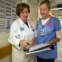 Theresa Capodilupo, left, a nurse director, and Brenda Pignone, a bedside nurse, review the daily patient assignment sheet for White 7, a post-surgery and trauma unit at Massachusetts General Hospital. (Jesse Costa/WBUR)