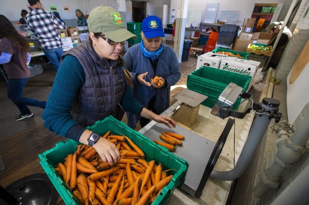 Daniela Marzuca, left, and Dalia Rosas of Whitemars Farm in Dracut weigh 1 lb bags of carrots at the New Entry Sustainable Farming Project in Lowell. (Jesse Costa/WBUR)