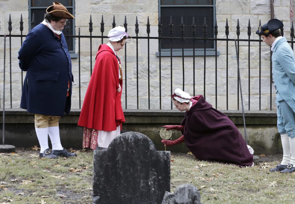 Actor-interpreters from the Boston Tea Party Ships and Museum, from left, Tim Lawton, Jillian Couillard, Sierra Grabowska and Stephen Chueka, place commemorative markers at Central Burying Ground. (Elise Amendola/AP)