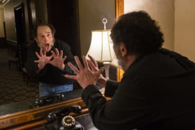 Actor Jeremiah Kissel recites a few lines from "A Christmas Carol" in the mirror used by Charles Dickens for rehearsals during his stays at the Omni Parker House. (Jesse Costa/WBUR)