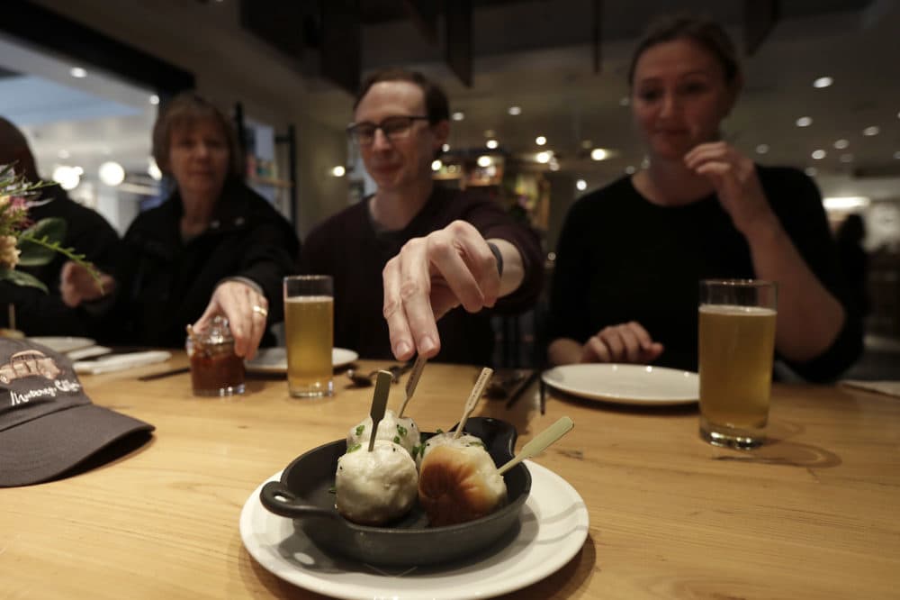 Mike Hardin, center, reaches for a dumpling while dining with others taking a tour with Avital Food Tours at China Live in San Francisco. (Jeff Chiu/AP)