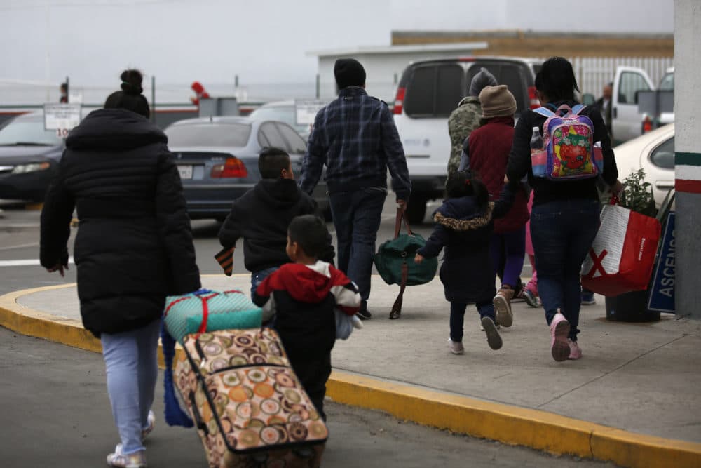 Migrants who have been a turn for an interview to request U.S. asylum walk to the El Chaparral pedestrian border crossing in Tijuana, Mexico, Friday, Dec. 21, 2018. (AP Photo/Moises Castillo)